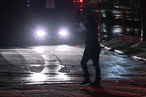 Dunkel gekleidete Fußgängerin überquert die Straße
